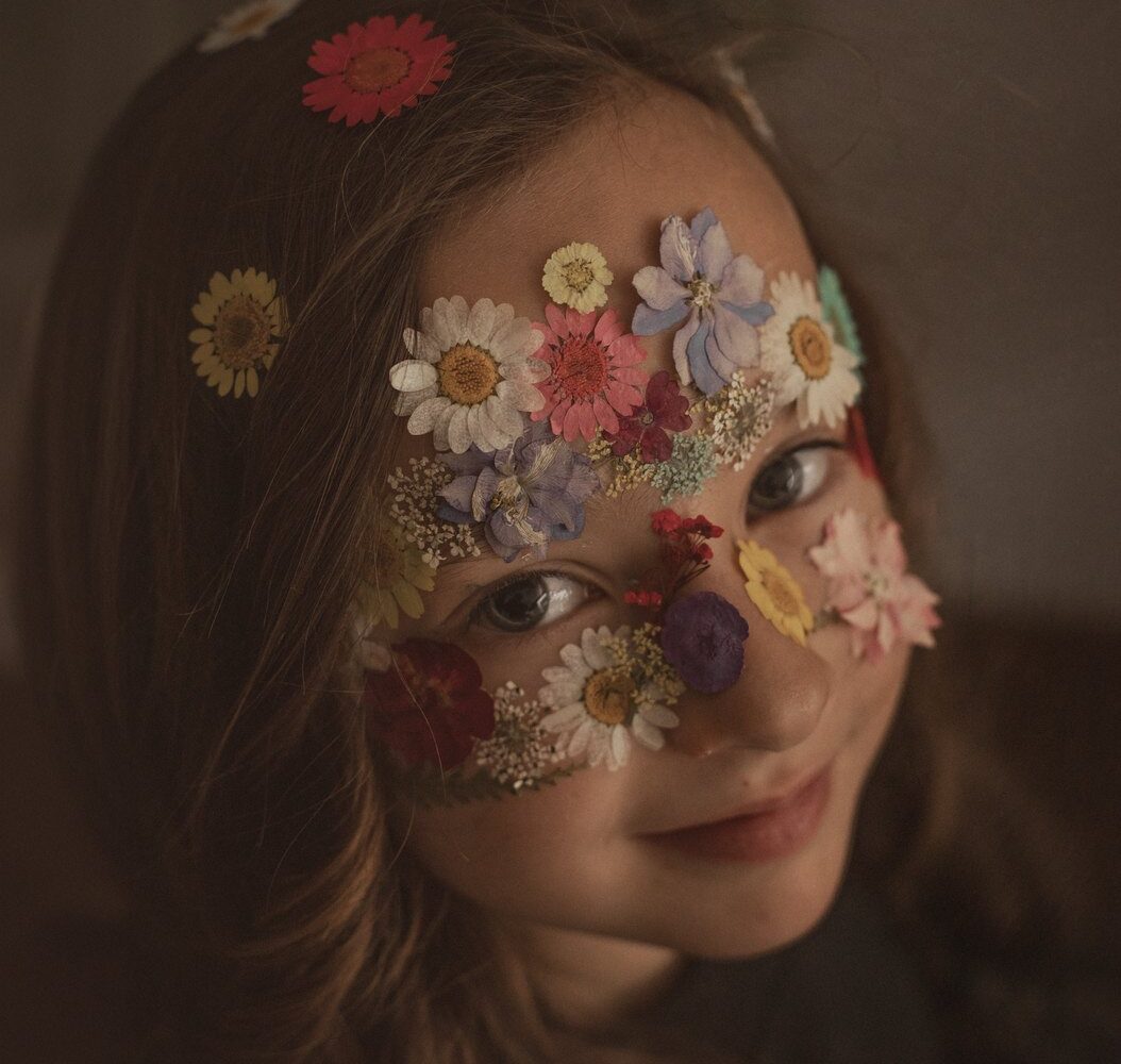 Niña con flores prensadas sobre la cara