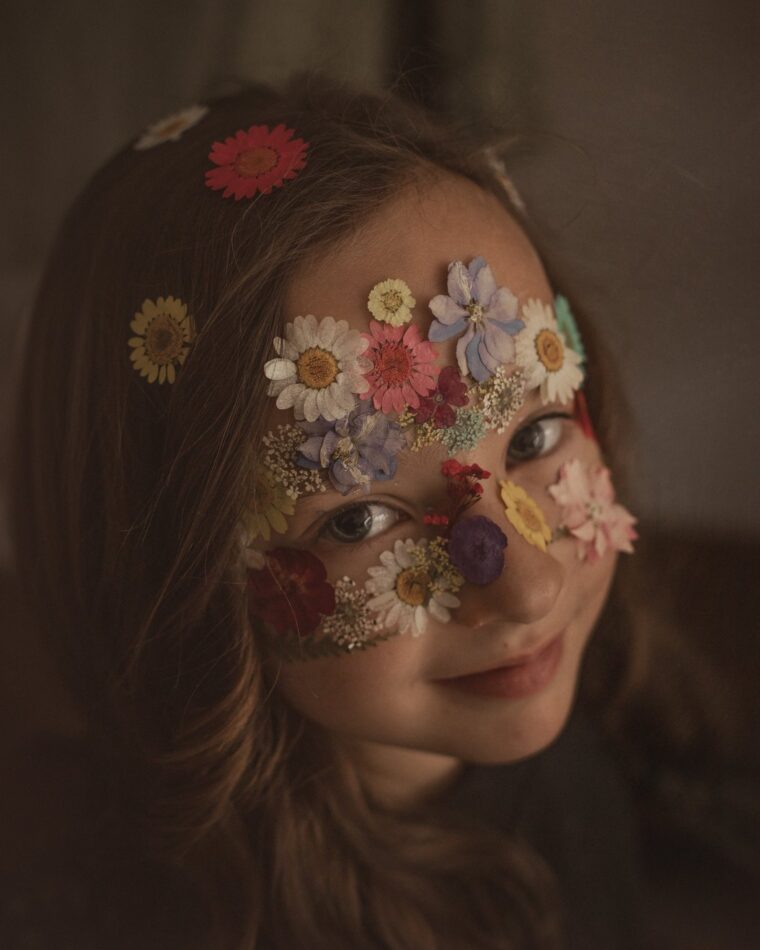 Niña con flores prensadas sobre la cara